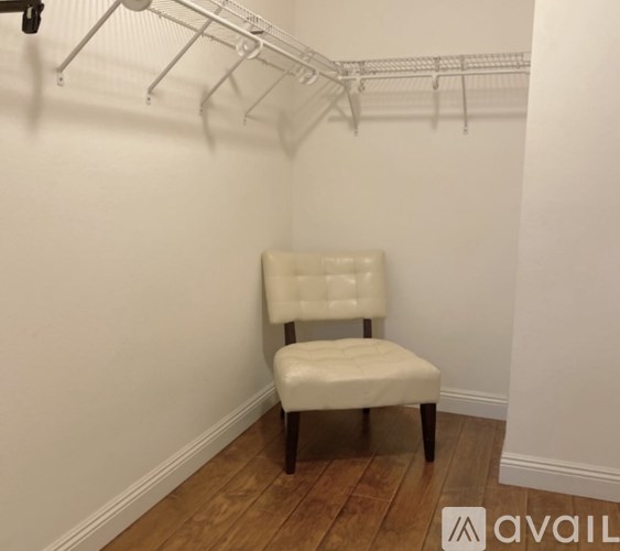 A white chair is placed in a room with a white wall and a wooden floor.