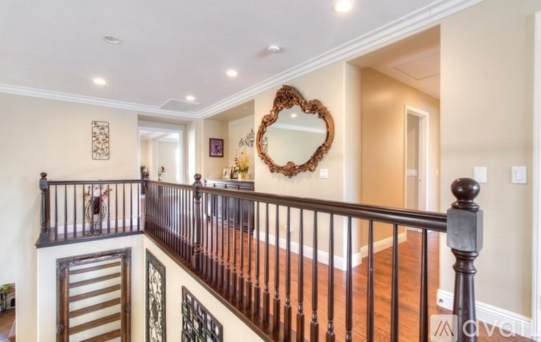 A staircase with a wooden banister and a heart-shaped mirror on the wall.