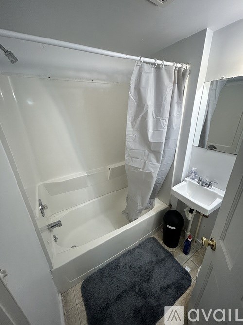 A bathroom with a white tub, sink, and shower curtain.