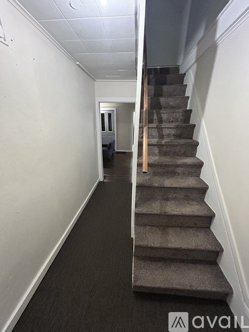 A staircase with a carpeted runner and wooden handrail.
