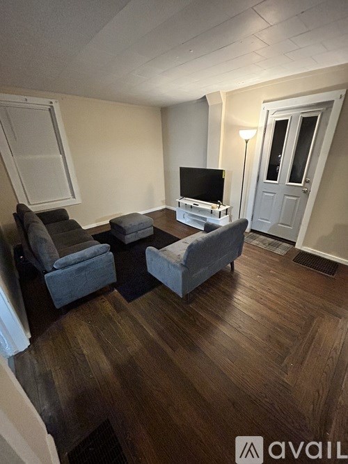 A living room with a grey couch and a television on a wooden stand.