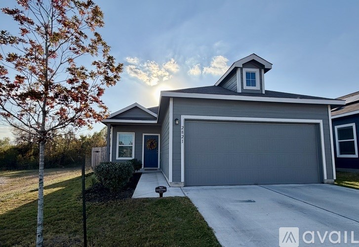A house with a garage and a tree in front of it.