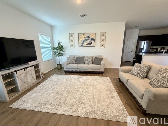 A living room with a grey couch, a white rug, and a television.