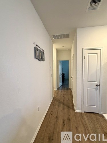 A hallway with a white door and a white wall.