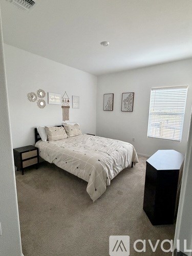 A bedroom with a bed, nightstand, and pictures on the wall.