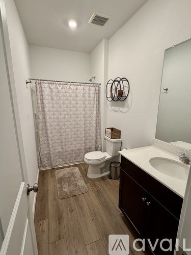 A bathroom with a toilet, sink, and shower curtain.