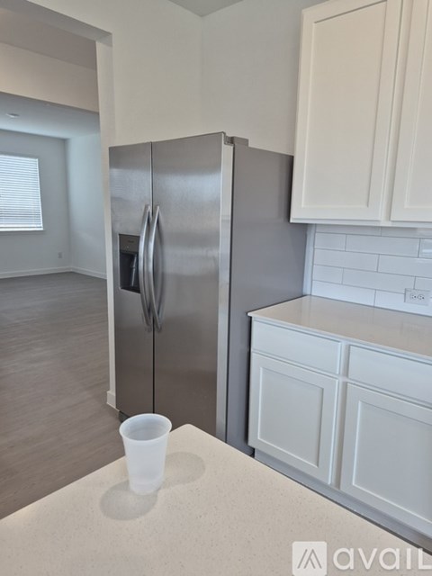 A kitchen with a stainless steel refrigerator and white cabinets.