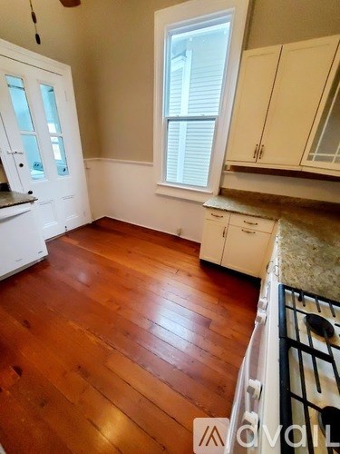 A kitchen with white cabinets and a wooden floor.