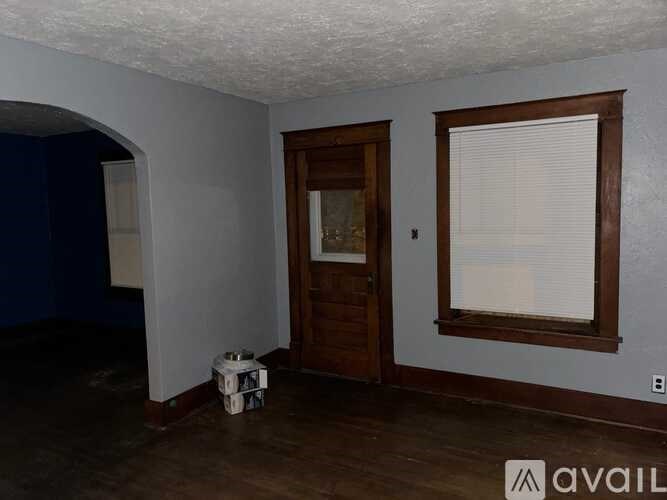 A room with a wooden door and a window with blinds.