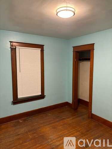 A room with wooden floors and a window with blinds.
