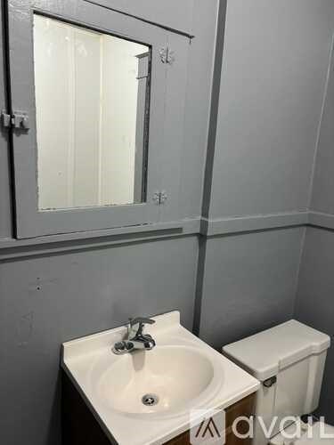 A bathroom with a toilet, sink, and mirror.