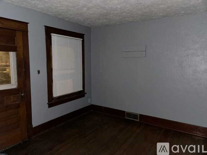 A room with a wooden door and a window with blinds.