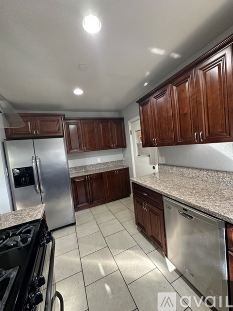 A kitchen with a stainless steel refrigerator and black stove top oven.