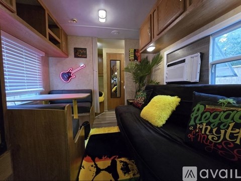 A living room with a couch and a guitar neon sign.