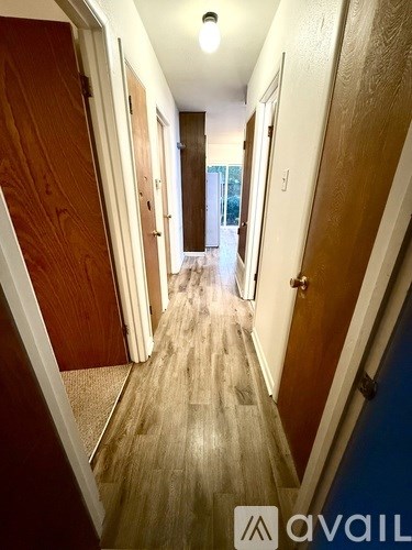 A long hallway with wooden floors and doors on either side.