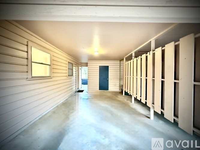 A long, narrow room with a series of windows on one side and a door at the far end.