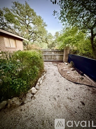 A gravel path leads to a house with a blue fence.