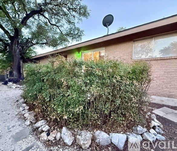 A house with a green light on the window and a tree in front.