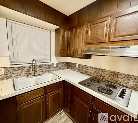 A kitchen with brown cabinets and a white sink.