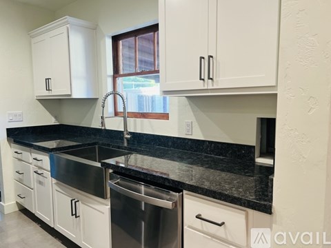 A kitchen with white cabinets and a black countertop.