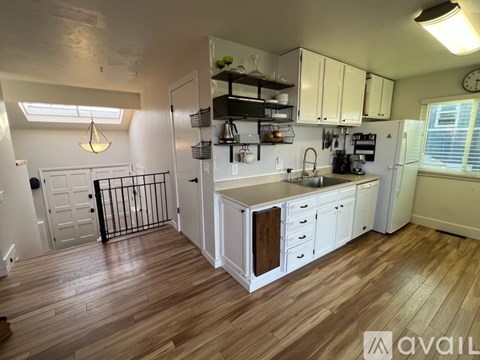 A kitchen with white cabinets and a wooden floor.