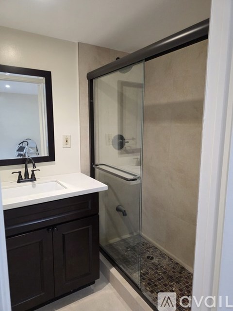 A bathroom with a white countertop and a walk-in shower.