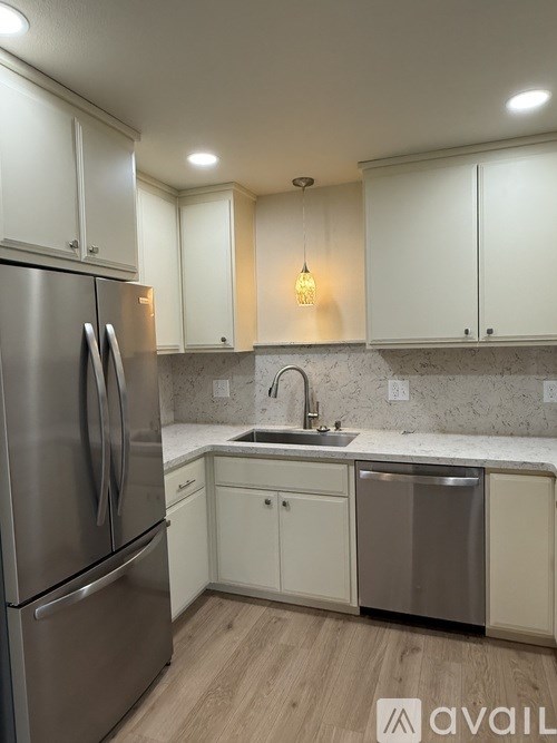 A kitchen with a stainless steel refrigerator and white cabinets.