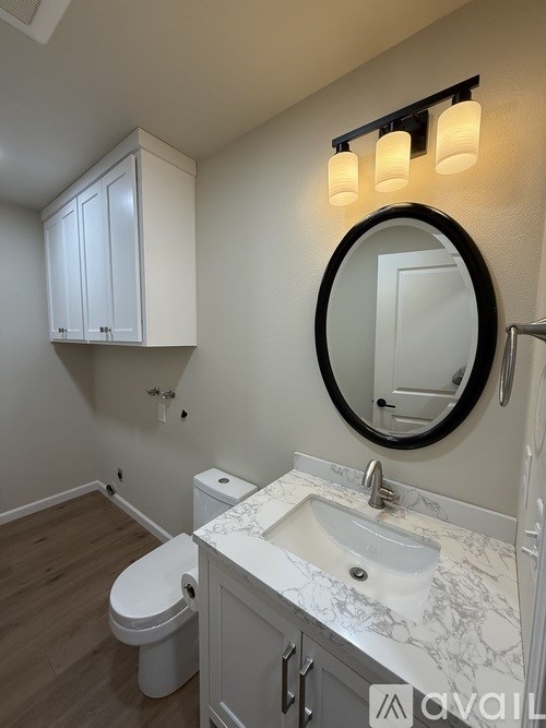 A bathroom with a toilet, sink, and a round mirror.