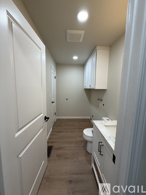 A bathroom with a toilet, sink, and cabinets.