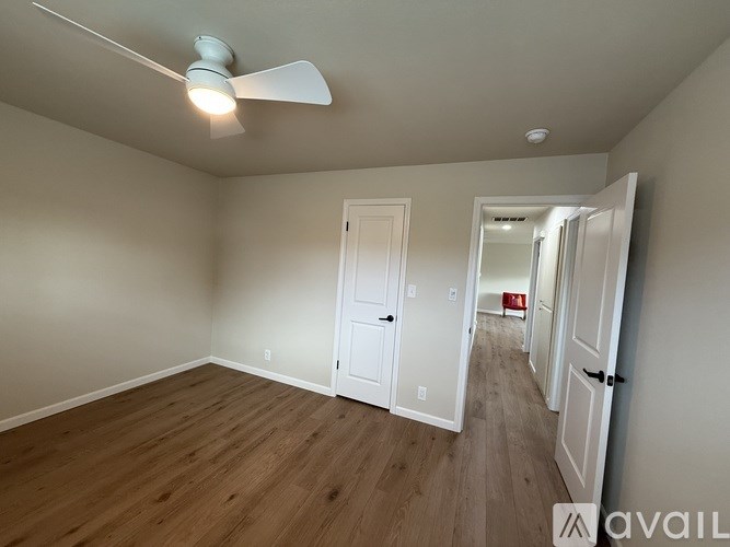 A room with a ceiling fan and wooden flooring.