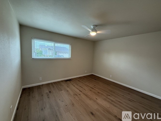 A room with a ceiling fan and a window with blinds.