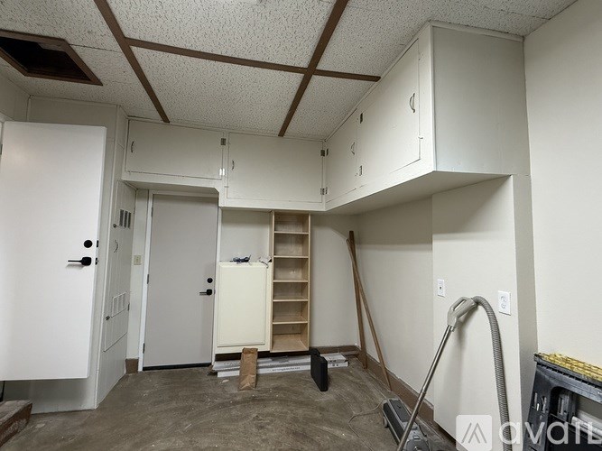 A room with a white door, a white cabinet, and a white wall.