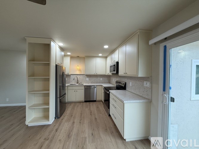 A kitchen with white cabinets and a wooden floor.