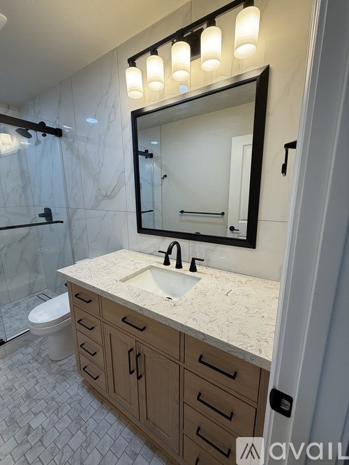 A bathroom with a marble countertop and a large mirror above it.