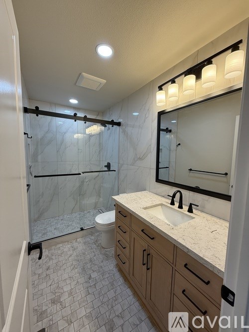 A bathroom with a marble countertop and a walk-in shower.