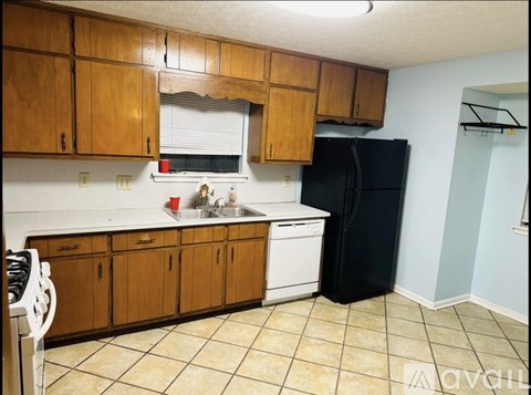 A kitchen with wooden cabinets and a black refrigerator.