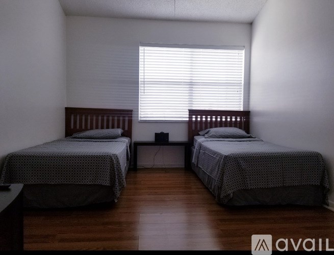 Two beds in a room with wooden floors and white walls.