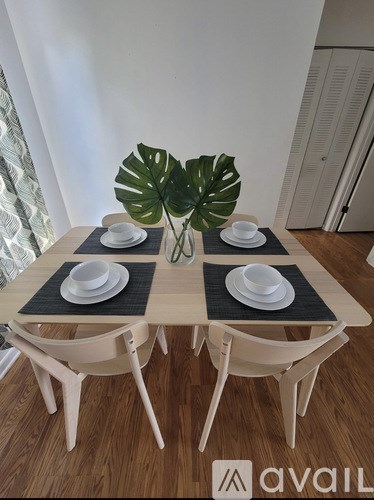 A table with a vase of leaves and four plates on it.