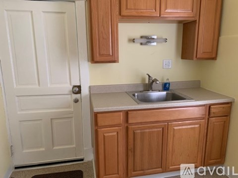 A kitchen with wooden cabinets and a white door.