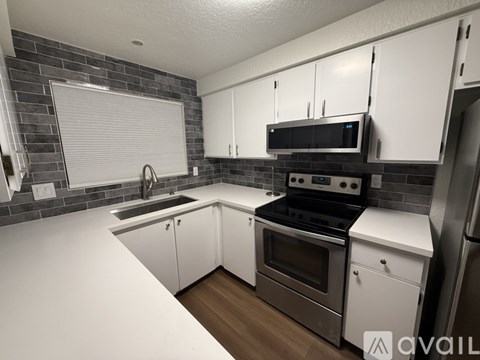 A kitchen with white countertops and a black stove top oven.