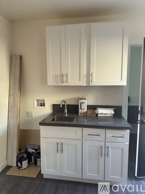 A kitchen with white cabinets and a black countertop.