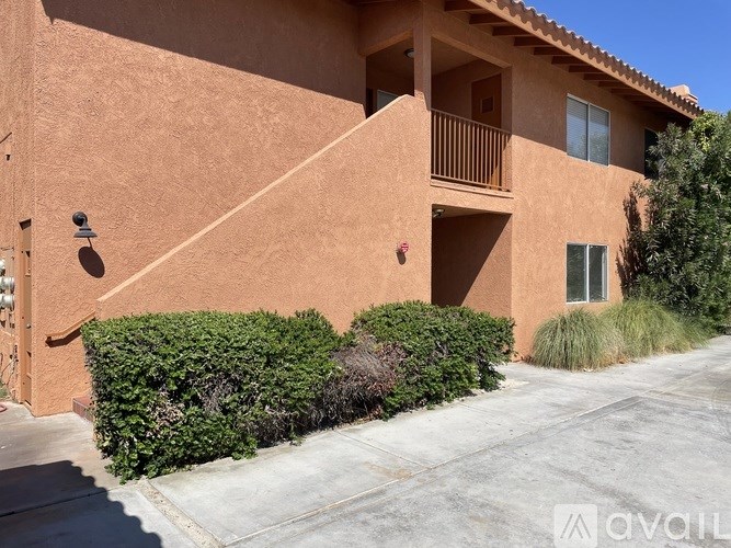 A house with a brown stucco exterior and a balcony on the second floor.