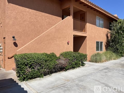 A house with a brown stucco exterior and a balcony on the second floor.