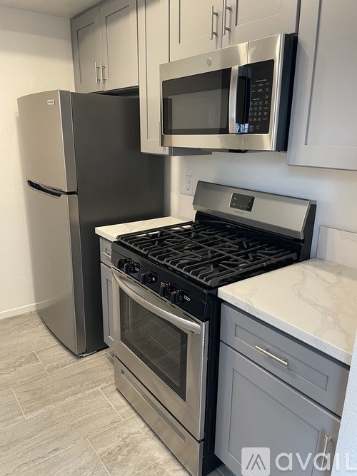 A kitchen with a stainless steel refrigerator, microwave, and oven.
