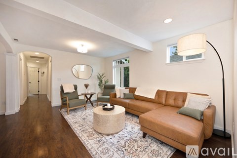 A living room with a brown leather couch and a round mirror on the wall.