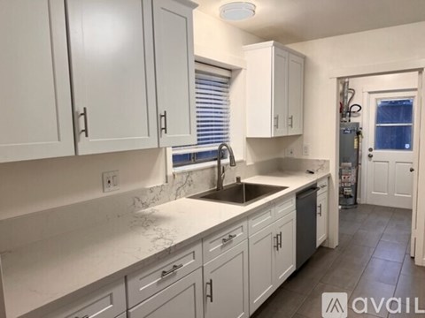 A kitchen with white cabinets and a marble countertop.