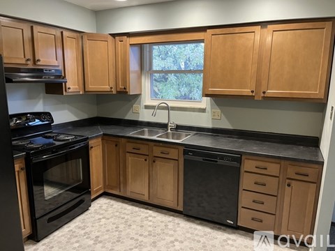 A kitchen with wooden cabinets and black appliances.