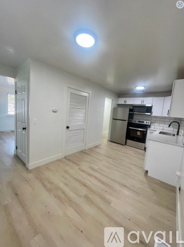 A kitchen with white cabinets and a wooden floor.