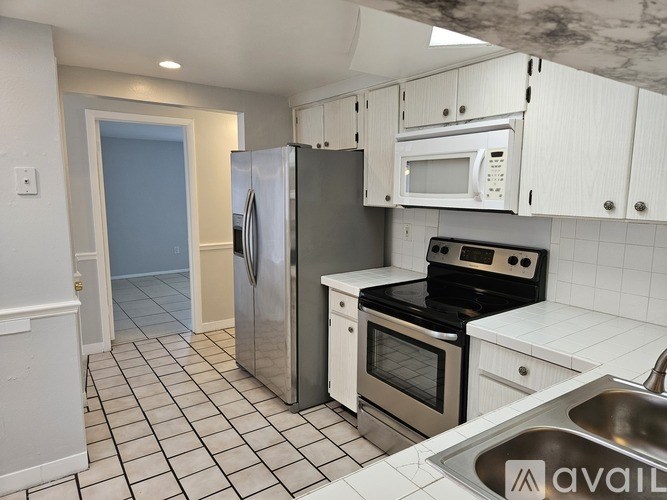 A kitchen with white cabinets and a stainless steel refrigerator.
