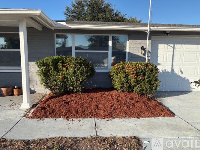 A house with a white garage door and a small garden in front.